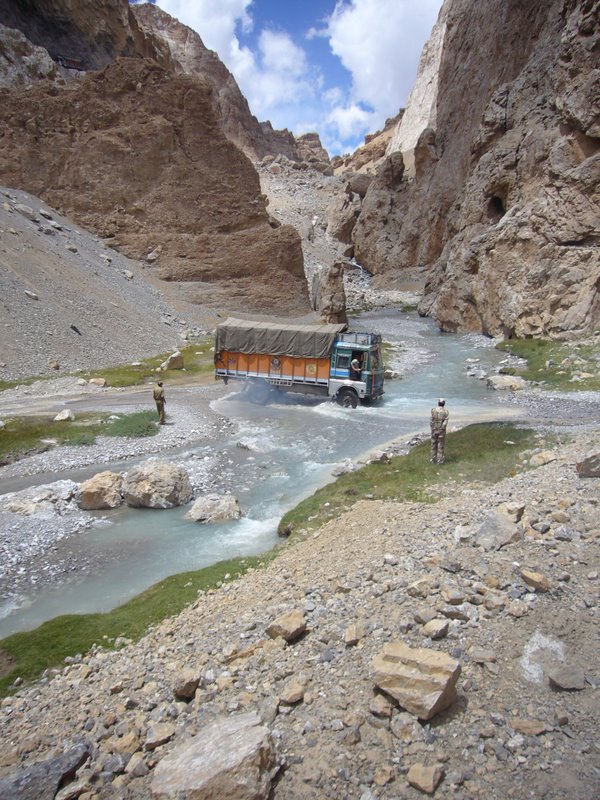 A truck crosses a stream with some difficulty.